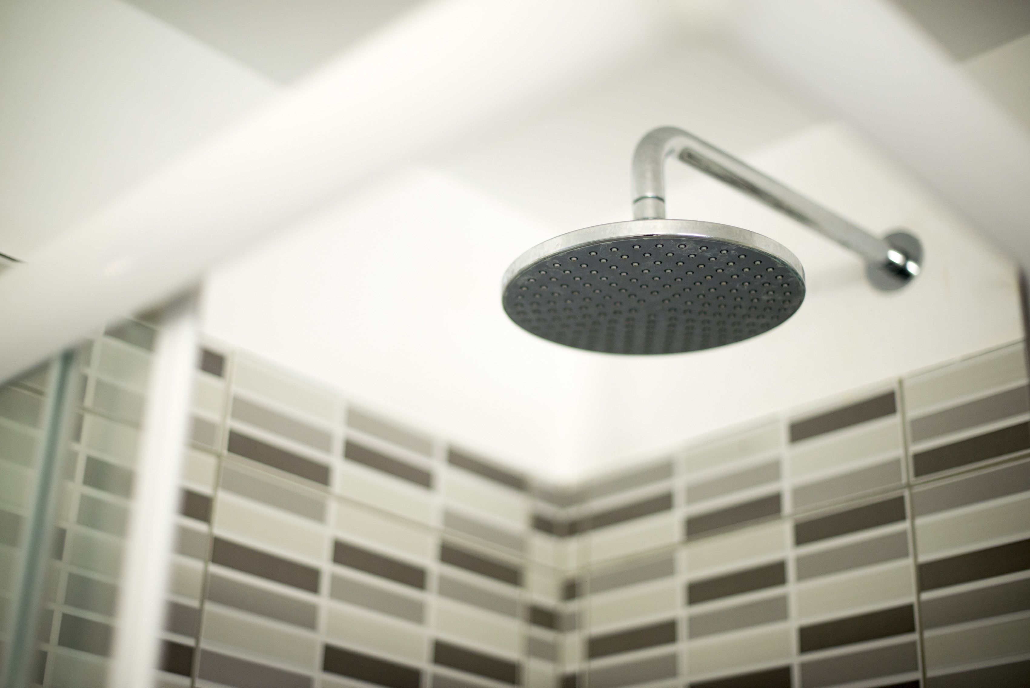 Un cabezal de ducha moderno en un baño de diseño minimalista y pared con azulejos.