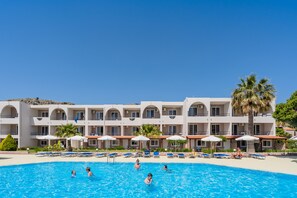 Un hotel con piscina, varios balcones y palmeras.