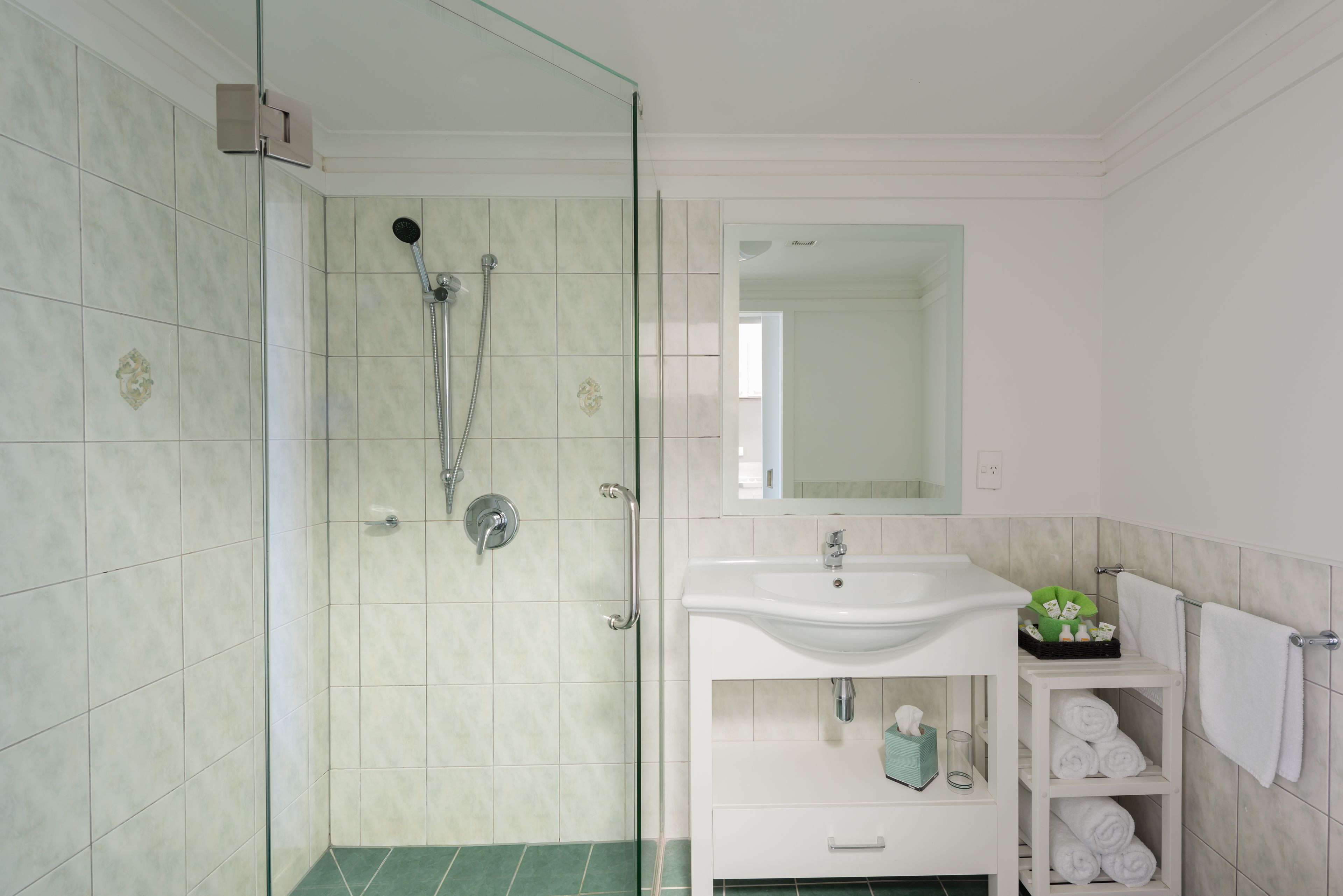A bathroom with a glass shower door, a white sink, and a mirror above it.