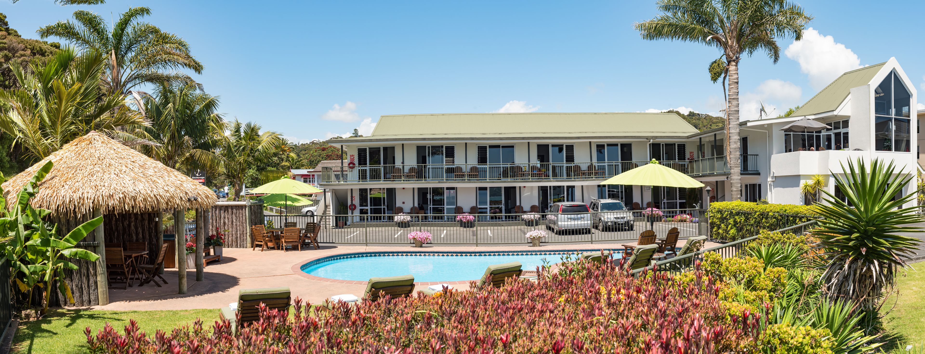 A resort with a swimming pool, outdoor seating, and a large building with multiple windows.