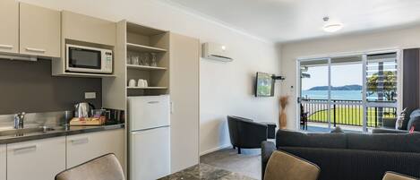 Una cocina moderna con microondas integrado, un refrigerador y un comedor con mesa y sillas de mármol.