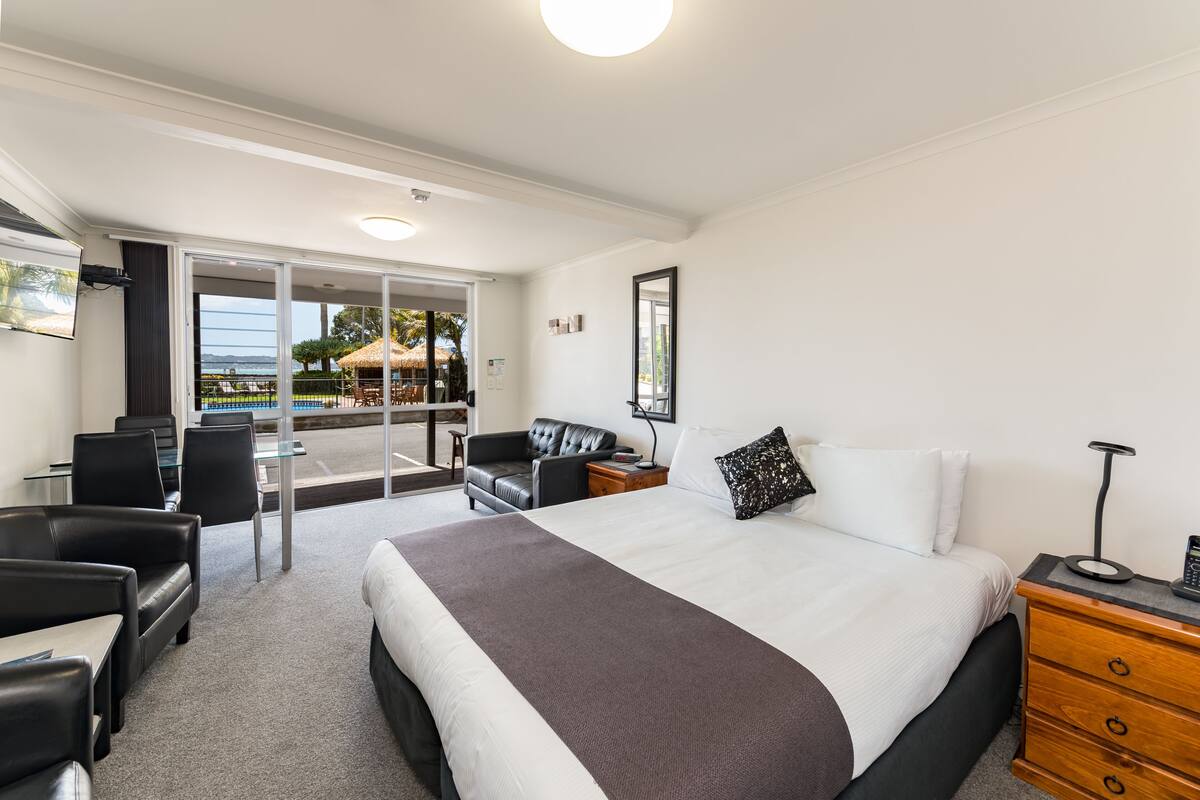 Una habitación de hotel con una cama grande, un escritorio y una zona de estar con vistas al mar.