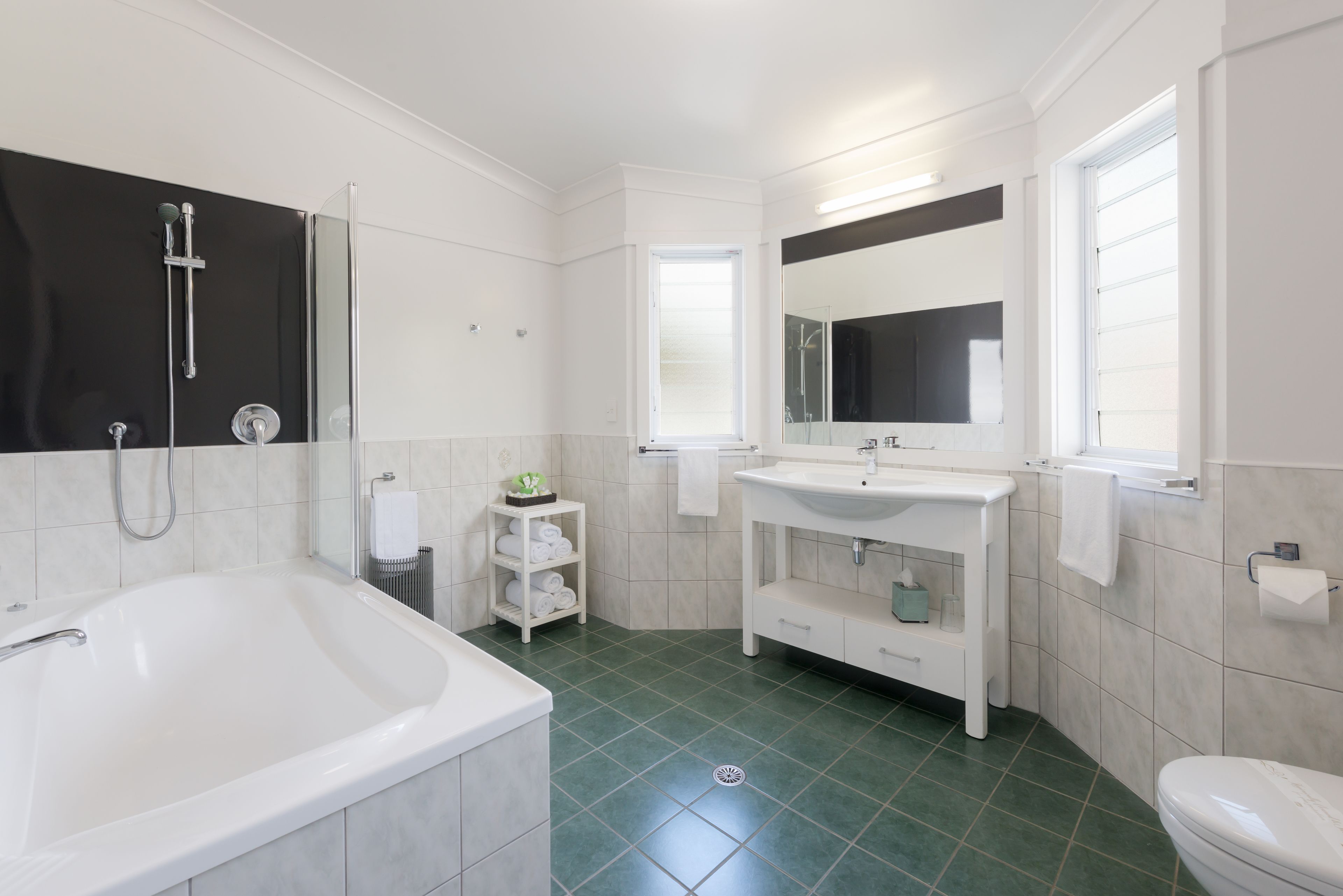 A modern bathroom with a bathtub, a sink, a mirror, and a toilet.