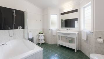 A modern bathroom with a bathtub, a sink, a mirror, and a toilet.