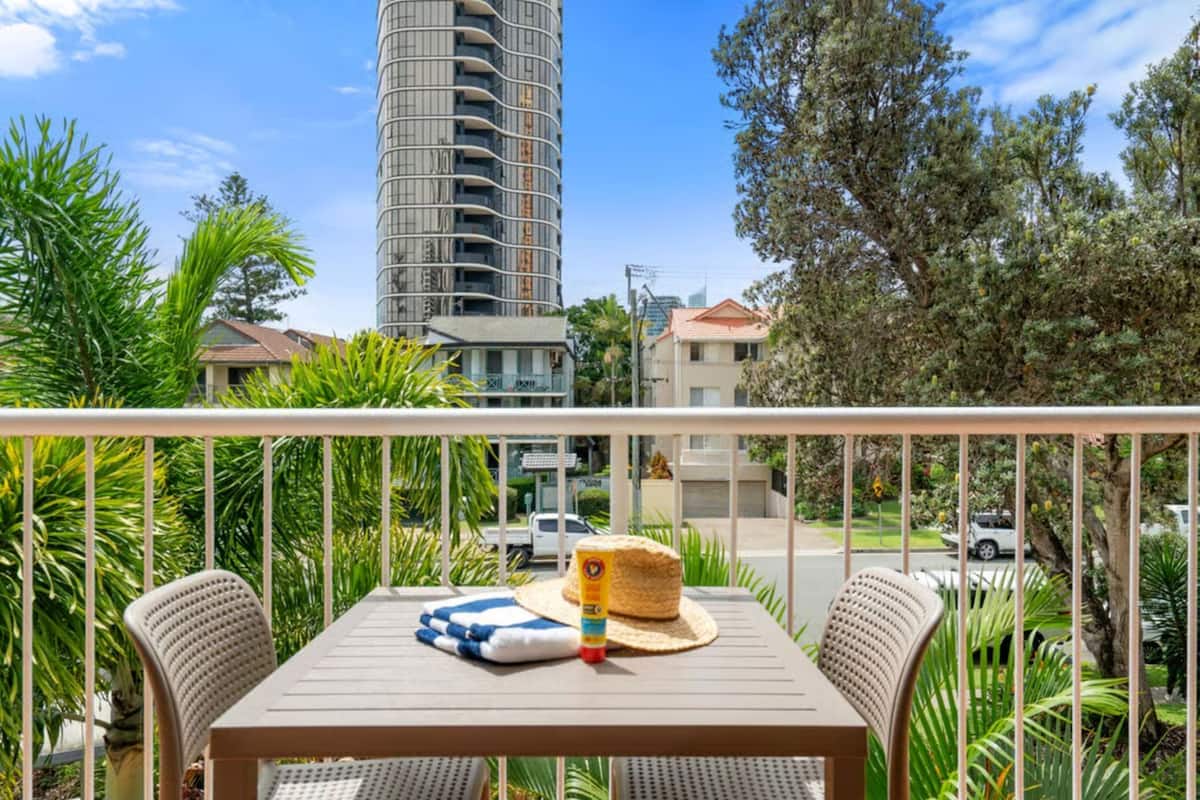 A balcony with a table, chairs, a hat, and a bottle.
