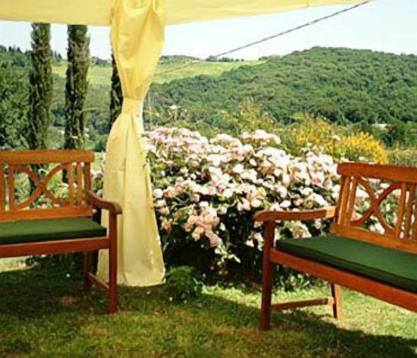 An outdoor seating area with two wooden benches and a yellow canopy.