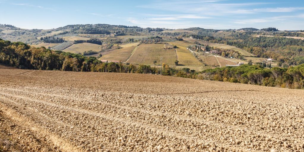 Ein weites Ackerfeld mit Terrassenfeldern und einem Dorf in der Ferne.
