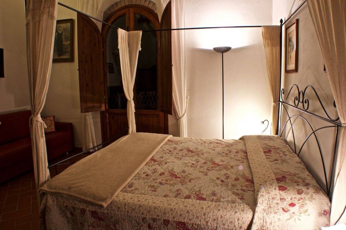 A bedroom with a four-poster bed, a wooden door, and a red sofa.