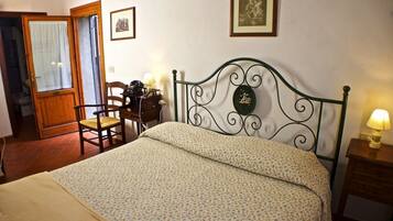 A bedroom with a bed, a chair, a desk, and a lamp.
