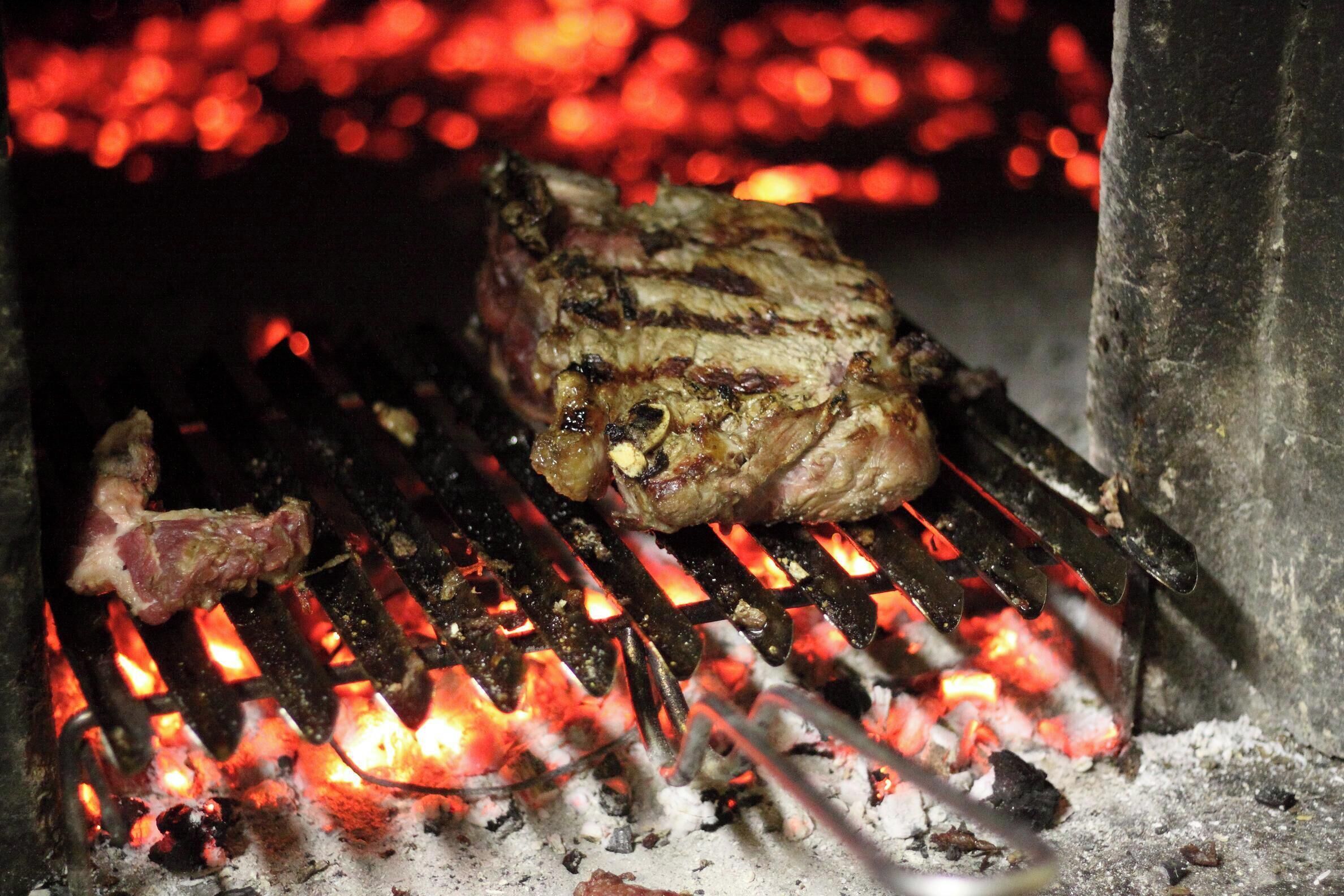 A steak grilling over an open flame.