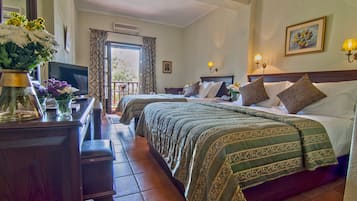 Habitación de hotel con dos camas, un escritorio con computadora, televisor y balcón con vistas.