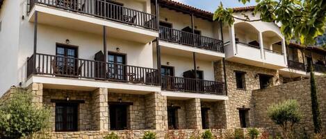 Un edificio de varios pisos con balcones, fachada de piedra y un jardín ajardinado.