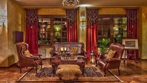 Ein traditionell eingerichtetes Wohnzimmer mit Kamin, Ledersesseln, einem Couchtisch und einer Pendelleuchte.