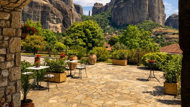 Eine Terrasse im Freien mit Steinböden, Topfpflanzen und Sitzmöbeln.