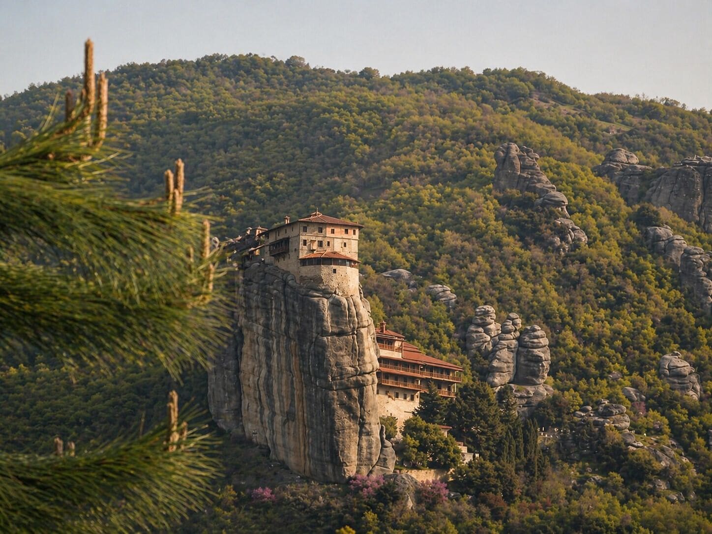 Ein Gebäude thront auf einer Klippe mit Blick auf einen bewaldeten Berg.