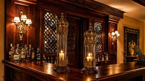 Eine Bar mit Holztresen, Spirituosenflaschen, dekorativen Kerzenhaltern und Wandleuchten.