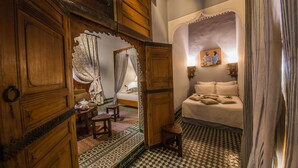 A traditional room with a checkered floor, wooden furniture, a bed with a canopy, and a painting on the wall. - Dar Victoria (Fes)