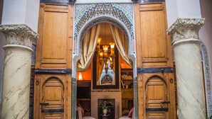 A traditional interior with wooden doors, a patterned rug, and a fireplace. - Dar Victoria (Fes)