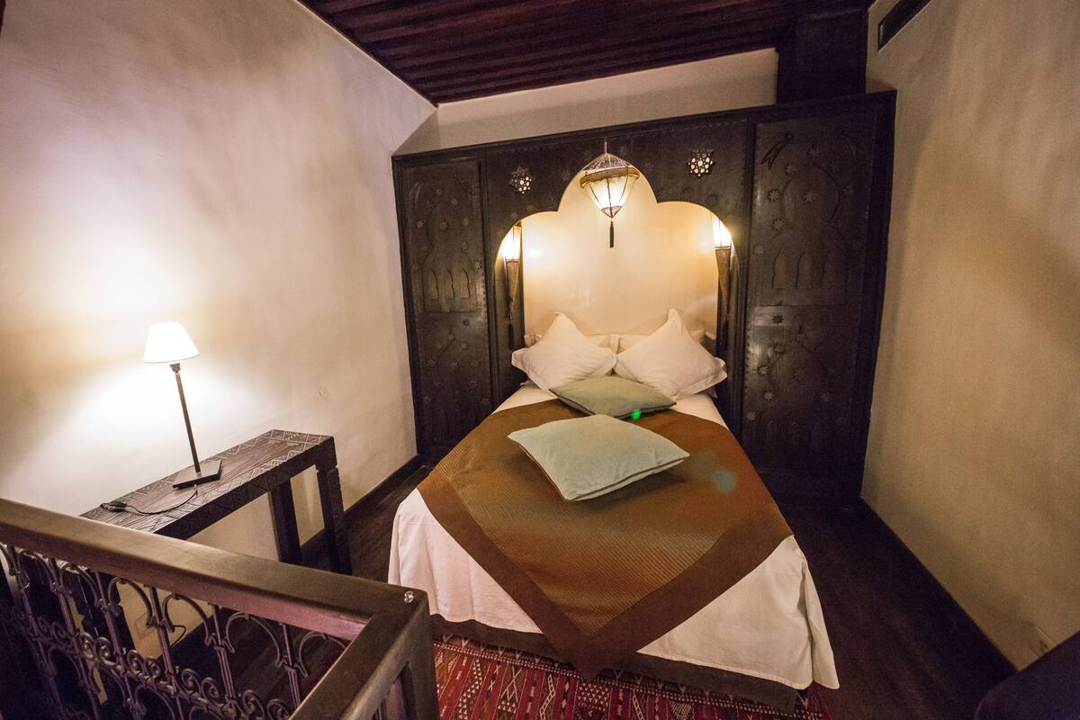 Une chambre à coucher comprenant un lit, une table de chevet, une lampe et une tête de lit décorative.