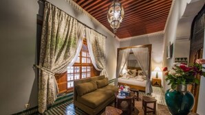 A cozy room with a checkered floor, a sofa, a small table, and a decorative vase. - Dar Victoria (Fes)