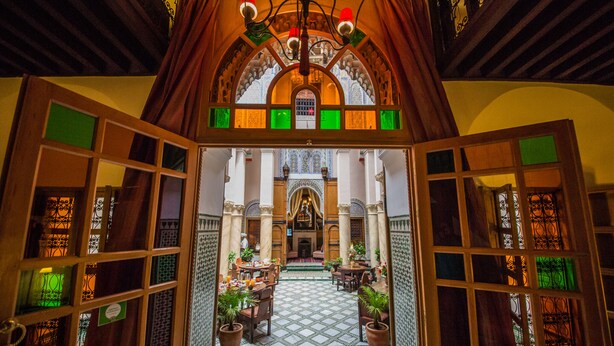 An ornate interior with a tiled floor, wooden furniture, and a chandelier. - Dar Victoria (Fes)