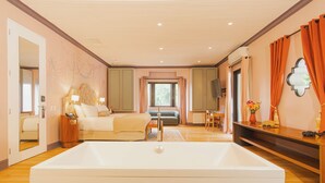 Ein geräumiges Zimmer mit einer großen Badewanne, einem Sofa, einem Esstisch und einem Fernseher.