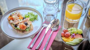 Una mesa con un plato de comida, un vaso de jugo de naranja, un tazón de fruta y una botella etiquetada 'Aubrey'.