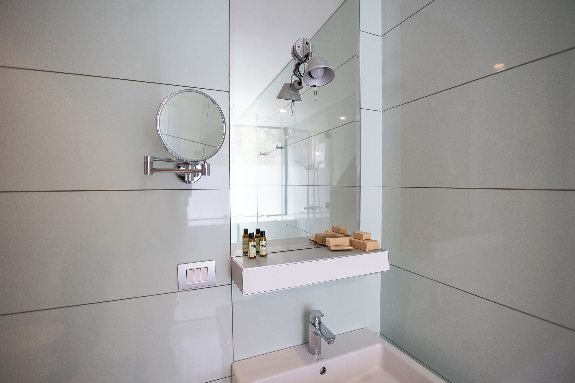 Un baño moderno con un espejo grande, tocador con artículos de aseo y ducha.