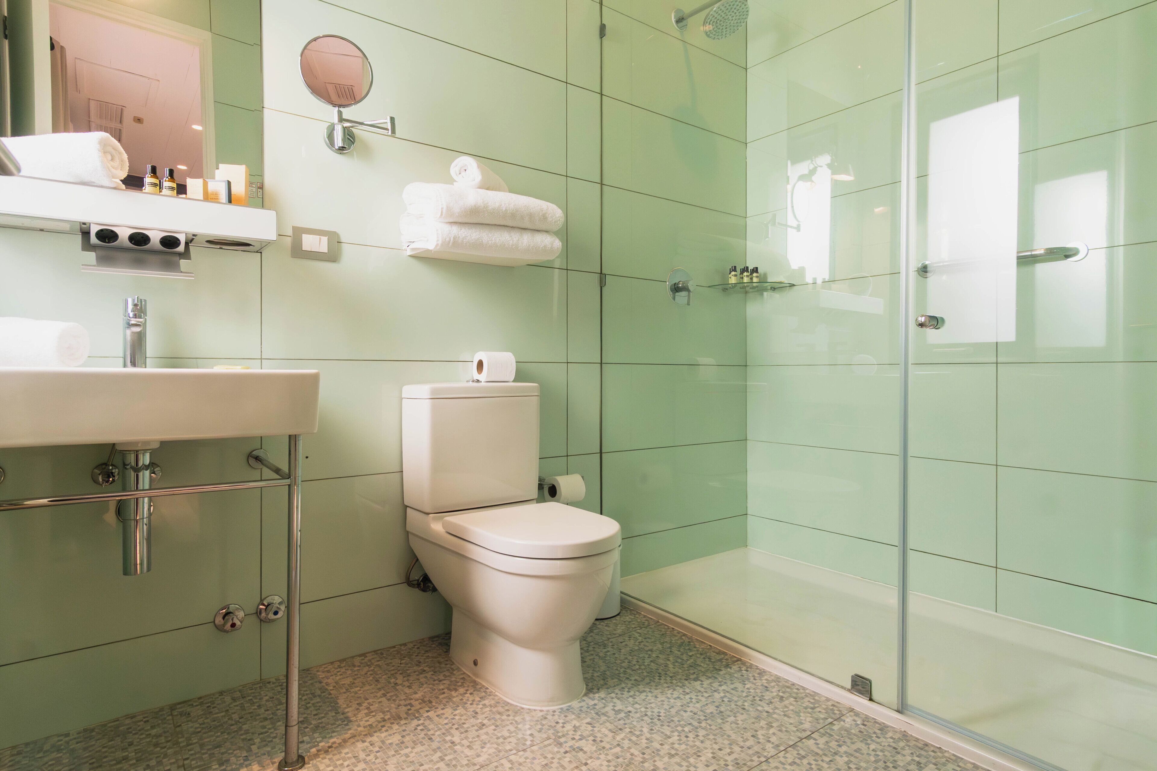 A bathroom with a toilet, sink, and glass shower enclosure.