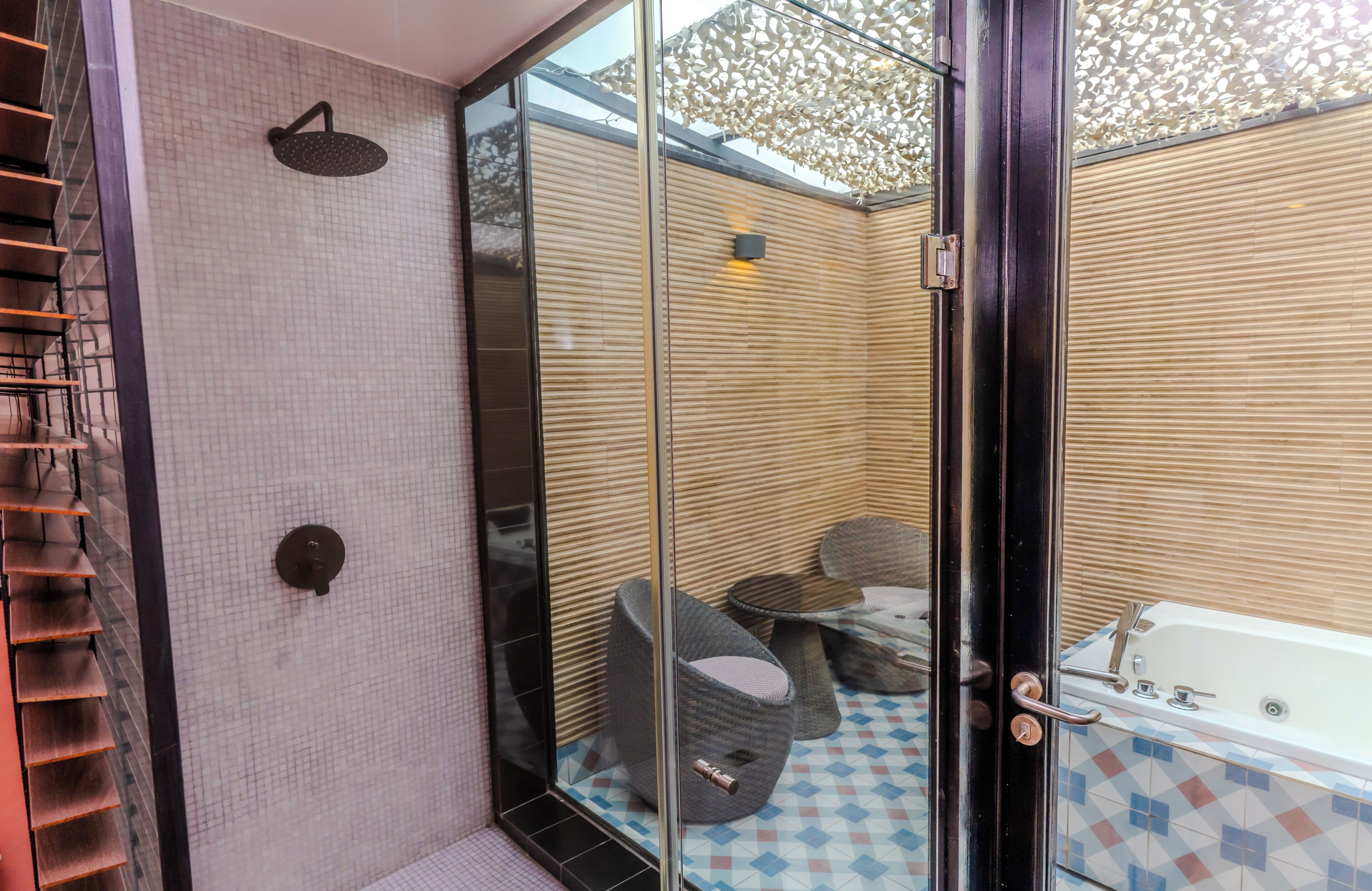 Une salle de bain moderne dotée d’une douche à parois de verre, d’une baignoire et d’un espace détente avec des fauteuils.