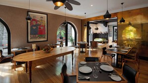 Ein Restaurant mit Holztischen und -stühlen, Deckenventilatoren und einem großen Gemälde an der Wand.