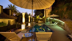 Ein Poolbereich mit Liegestühlen, Sonnenschirmen und einem Pool.