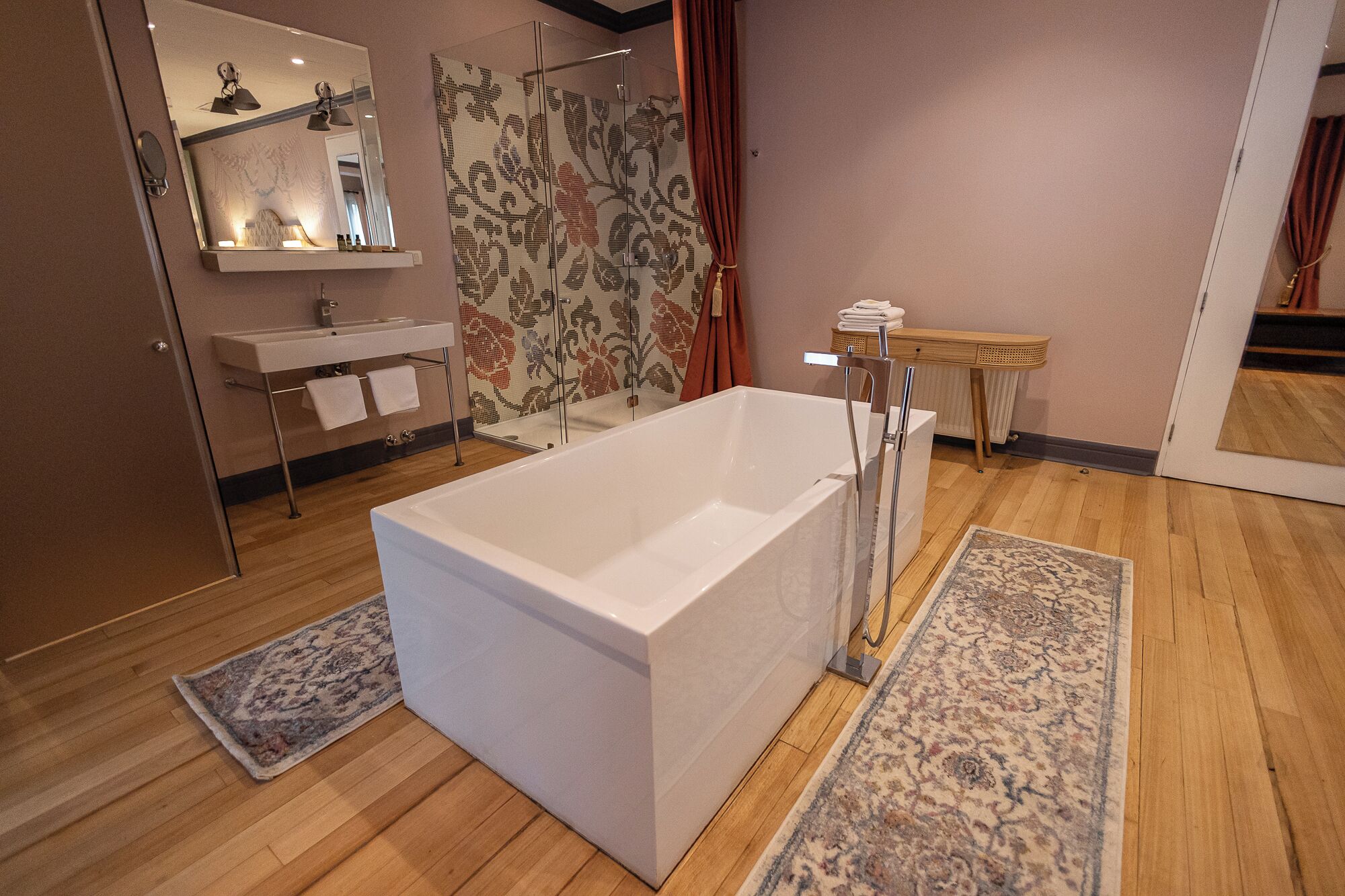 A modern bathroom with a large bathtub, a sink, a mirror, and a shower area.