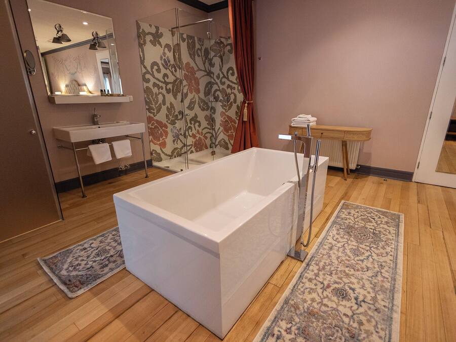 A modern bathroom with a large bathtub, a sink, a mirror, and a shower area.