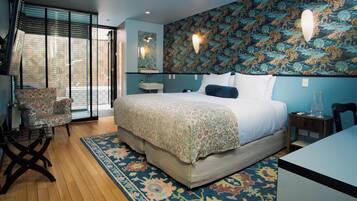 A bedroom with a large bed, a chair, a desk, and a patterned wall.