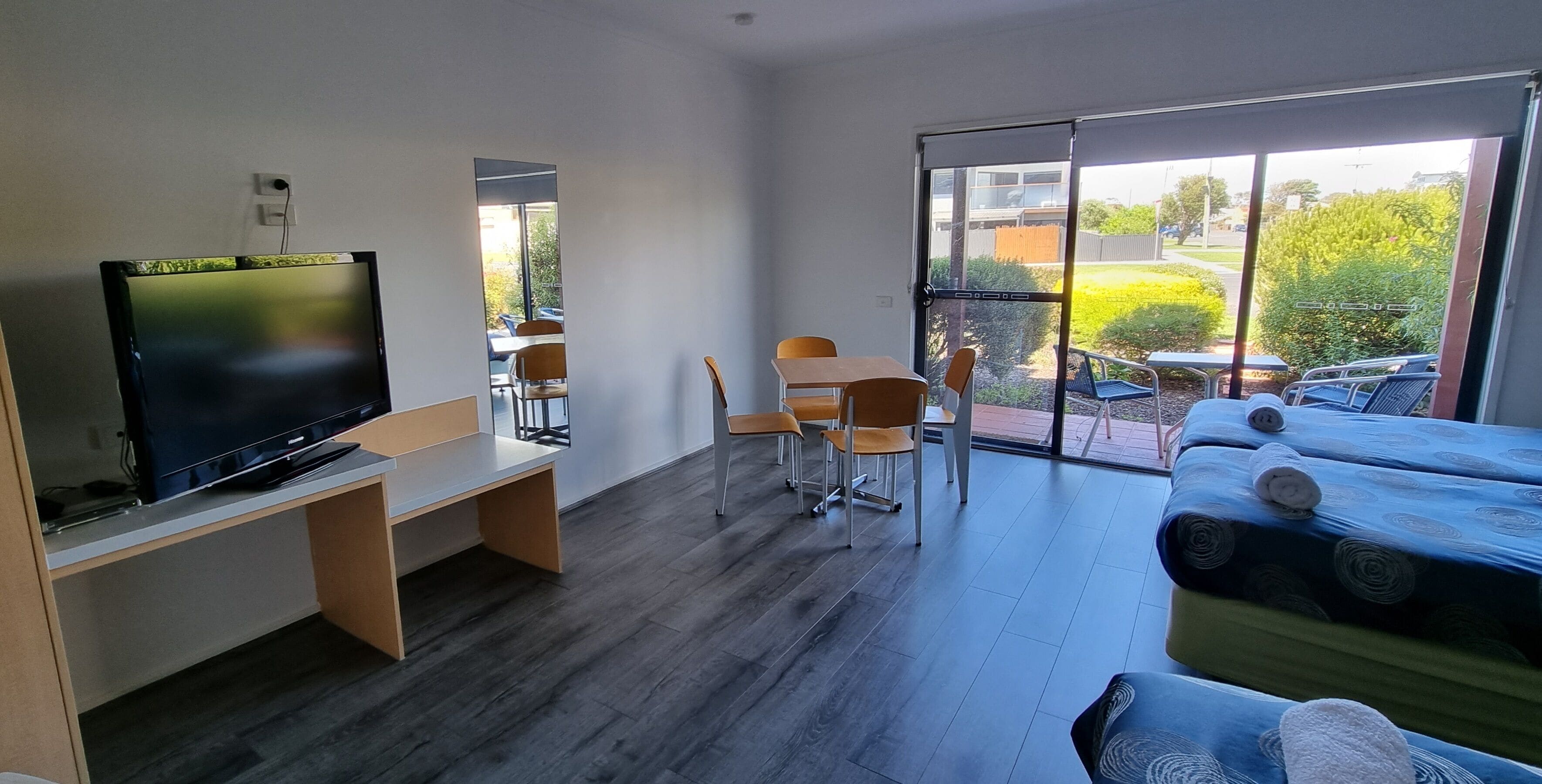 Une chambre moderne équipée d’une télévision, d’un bureau, d’un canapé et d’un balcon avec coin salon extérieur.