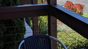 A balcony with a wicker chair, a view of the ocean, and a road in the background. - Seaview Motel and Apartments (Apollo Bay)