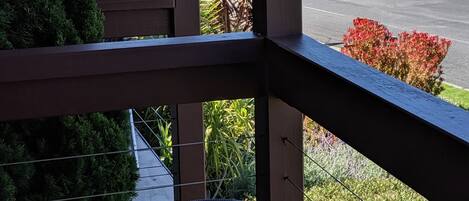 A balcony with a wicker chair, a view of the ocean, and a road in the background.