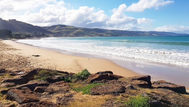 A beach with a sandy shore, rocky outcrops, and distant hills under a clear sky. - Seaview Motel and Apartments (Apollo Bay)