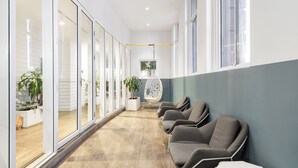 A modern waiting area with a long bench, glass doors, and a hanging chair. - YHA Sydney Central (Haymarket)