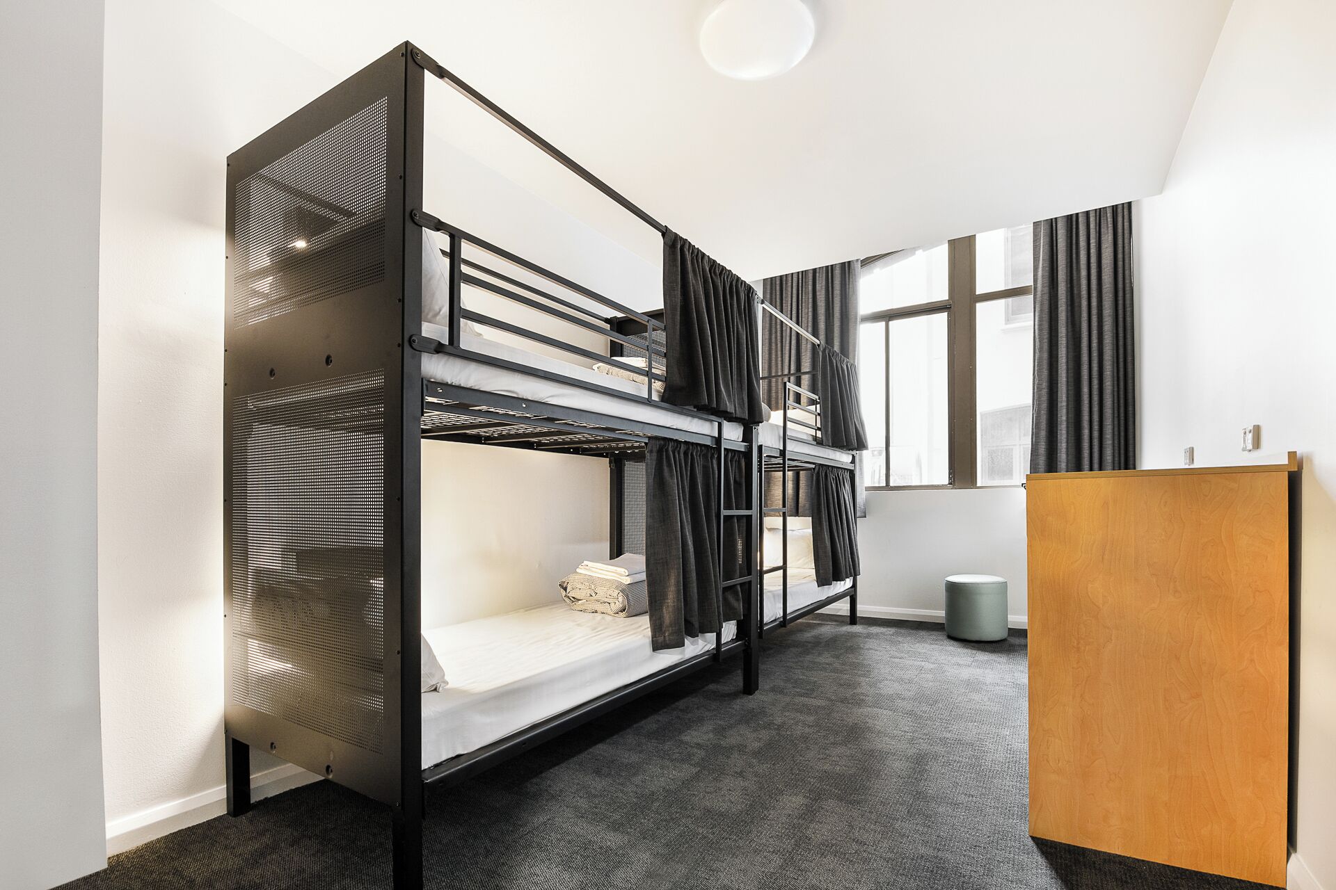 Une chambre avec un lit superposé, un bureau en bois et une poubelle.