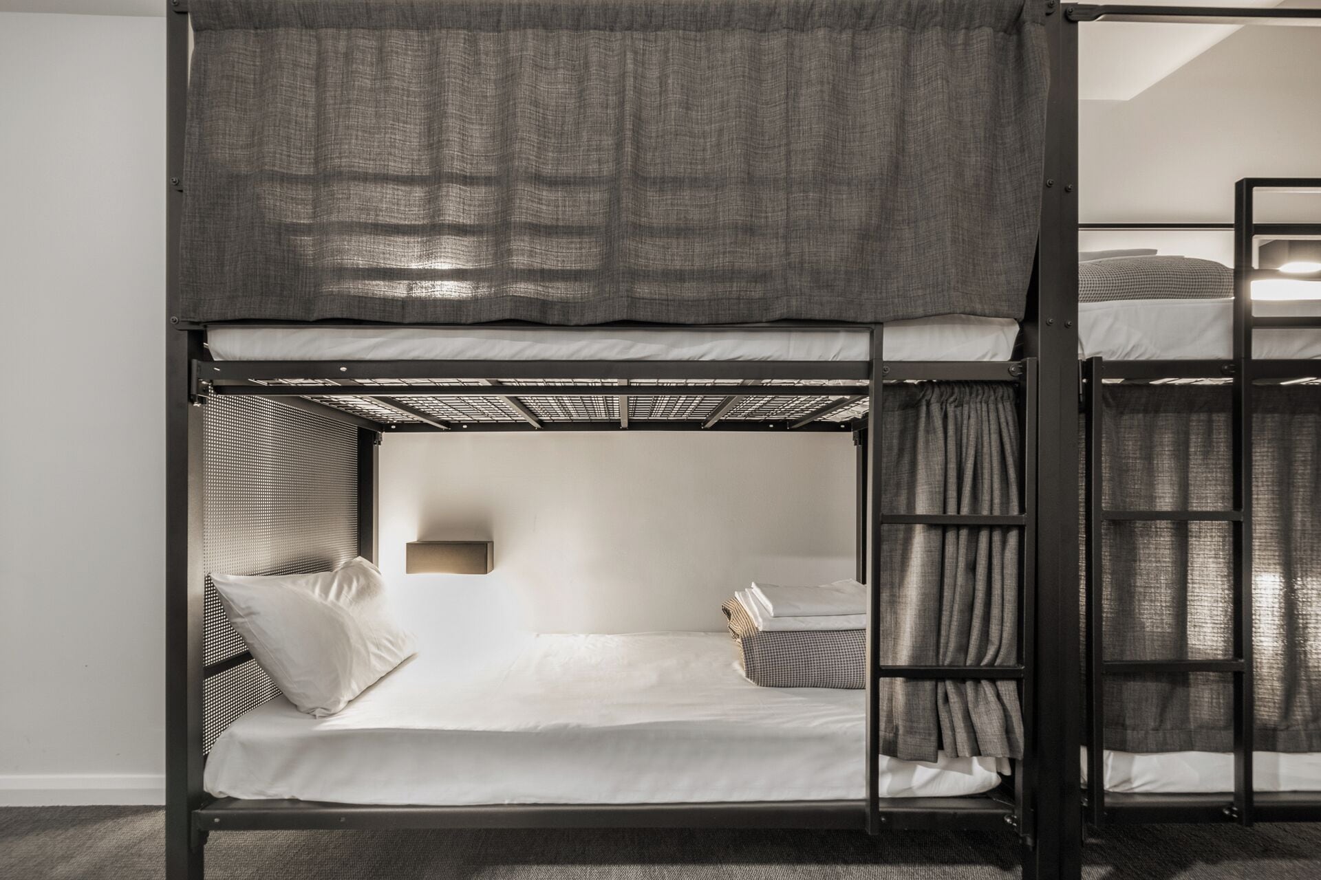 A bunk bed with a headboard, a bedside table, and curtains.