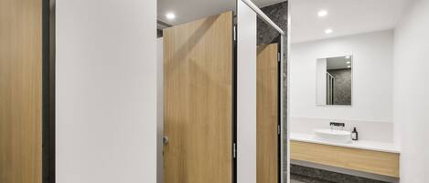 A modern bathroom with a wooden vanity, a mirror, and a white sink.