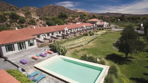 A hotel with a swimming pool, outdoor seating, and a view of the surrounding hills. - Hotel Huacalera (Huacalera)