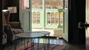 A room with a view of mountains through a green door, a chair, a table, and a rug. - Hotel Huacalera (Huacalera)