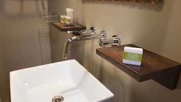 Un baño con un lavabo blanco, un tocador de madera y un dispensador de jabón sobre el tocador.