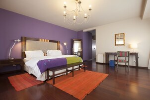 Un dormitorio con cama, mesitas de noche, un banco, un escritorio y una silla.