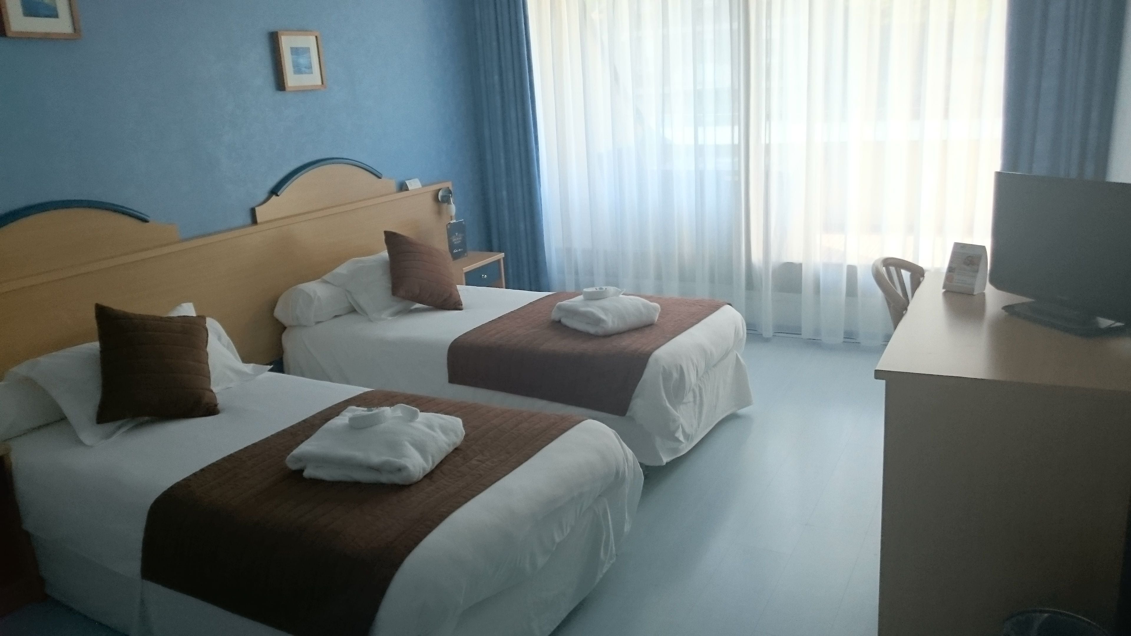 Una habitación de hotel con dos camas, un escritorio y una televisión.