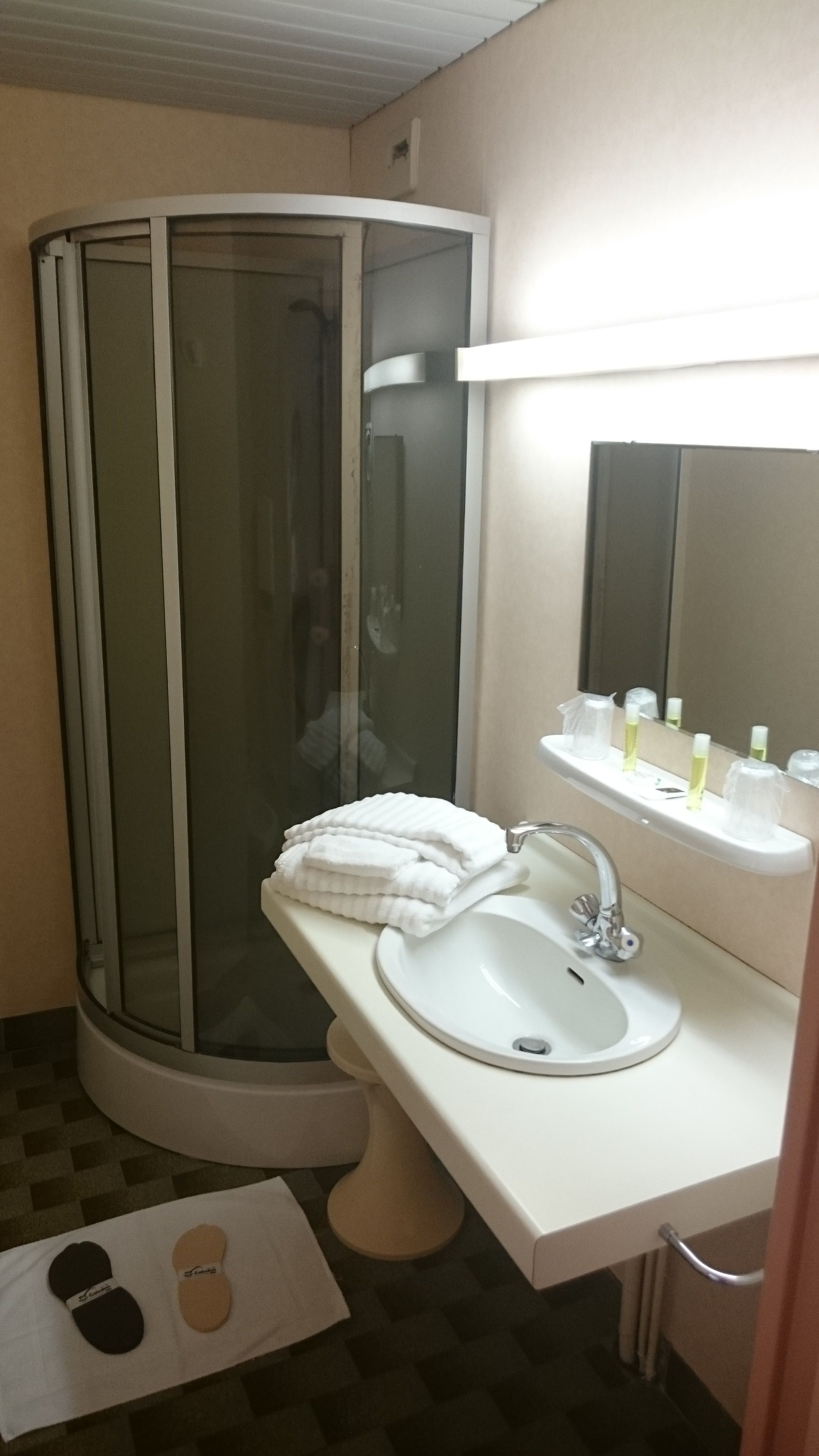 Un baño con cabina de ducha de vidrio, un lavabo con espejo y un perchero para toallas.