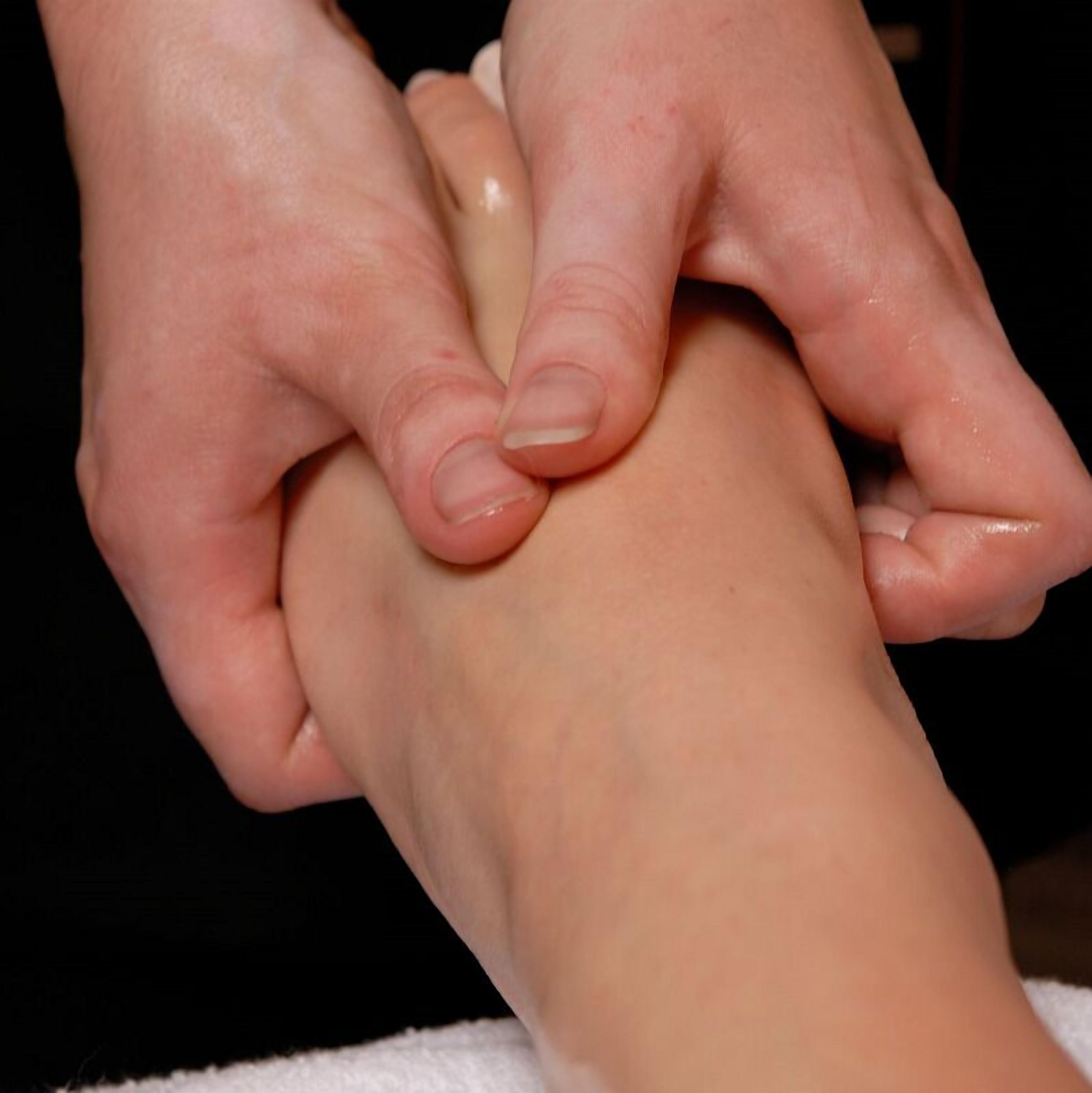 A close-up of hands performing a massage on a foot.